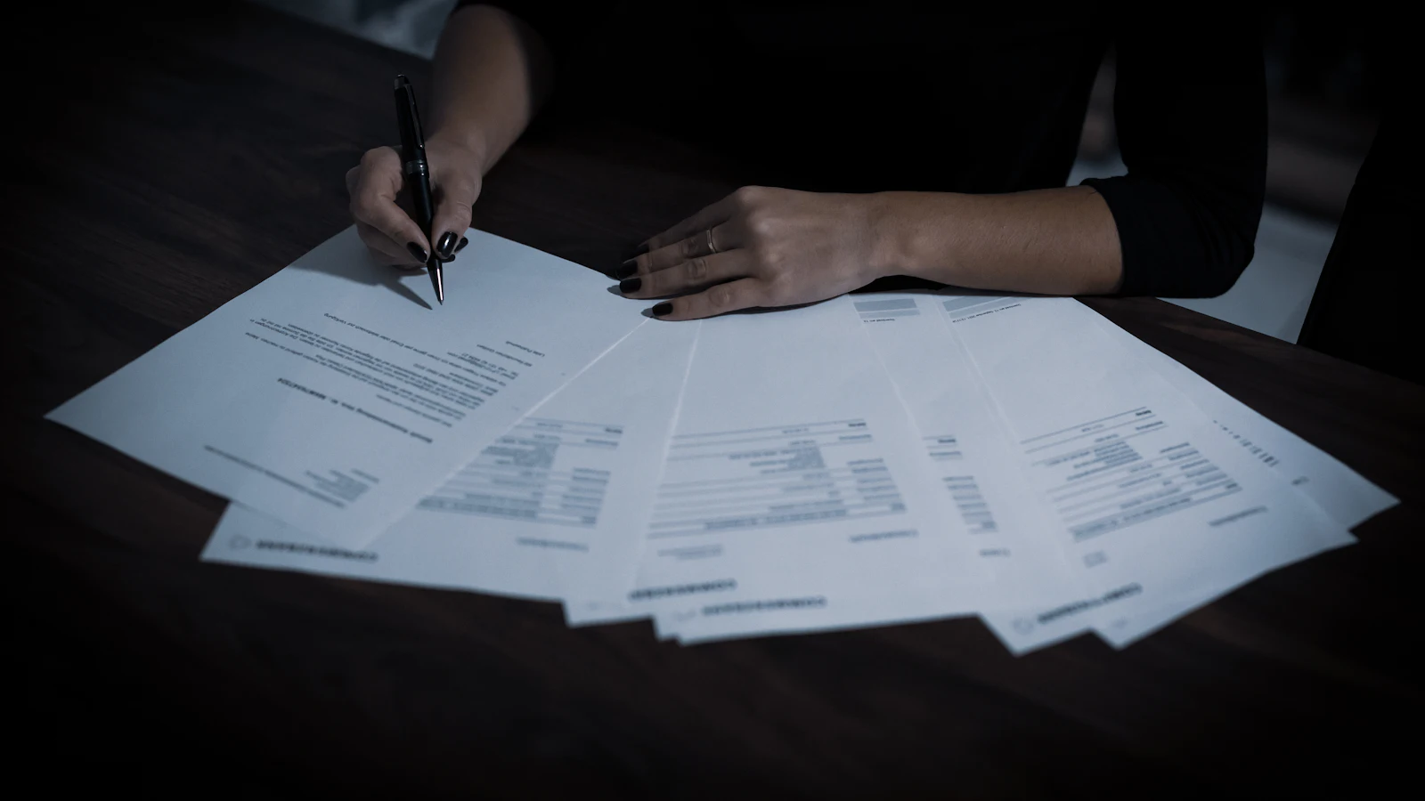 A woman sitting at a table covered with paperwork
